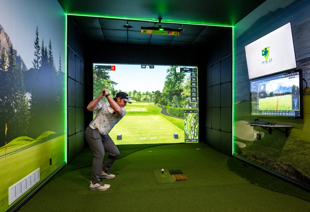 Golfer mid-swing while playing a round in a custom home golf simulator